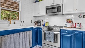 A kitchen with white cabinets, a blue countertop, a stainless steel stove, and a microwave. - Lenoir Cottage (Athens)