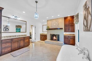 A spacious bathroom with a large bathtub, a fireplace, and a mirror above the sink. - The Wexford French Chateau w/ Pool (Athens)