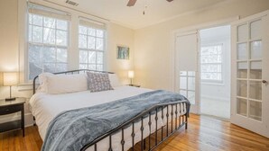 Une chambre à coucher avec un lit, des lampes de chevet, un ventilateur de plafond et une porte donnant sur un balcon.