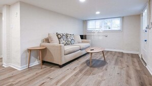 A living room with a beige sofa, two small side tables, a coffee table, and a window with blinds. - Bobbin Mills Studio - 1 Mile From Downtown Athens (Athens)