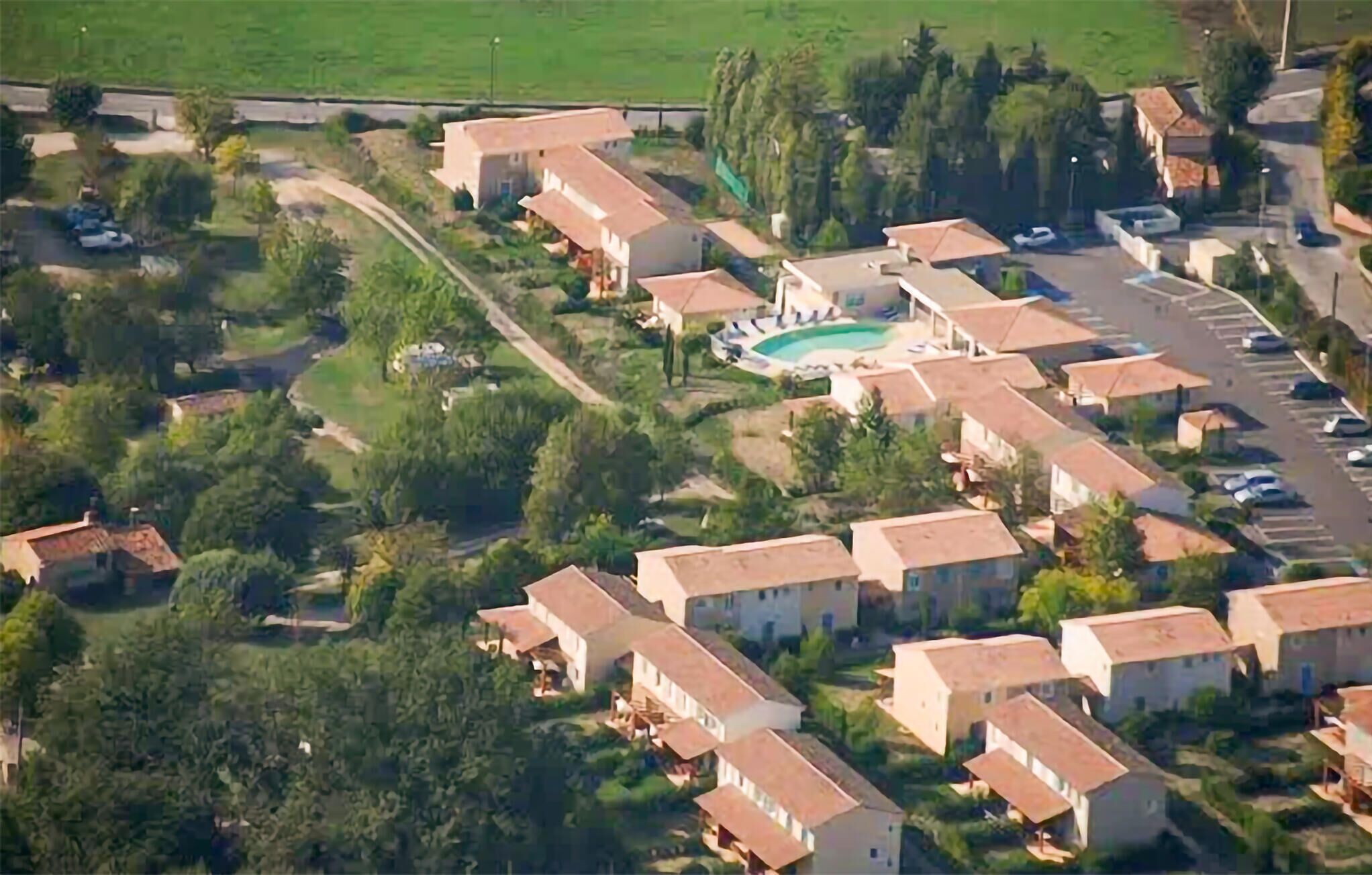 An aerial view of a residential area with multiple houses, a swimming pool, and a parking lot.