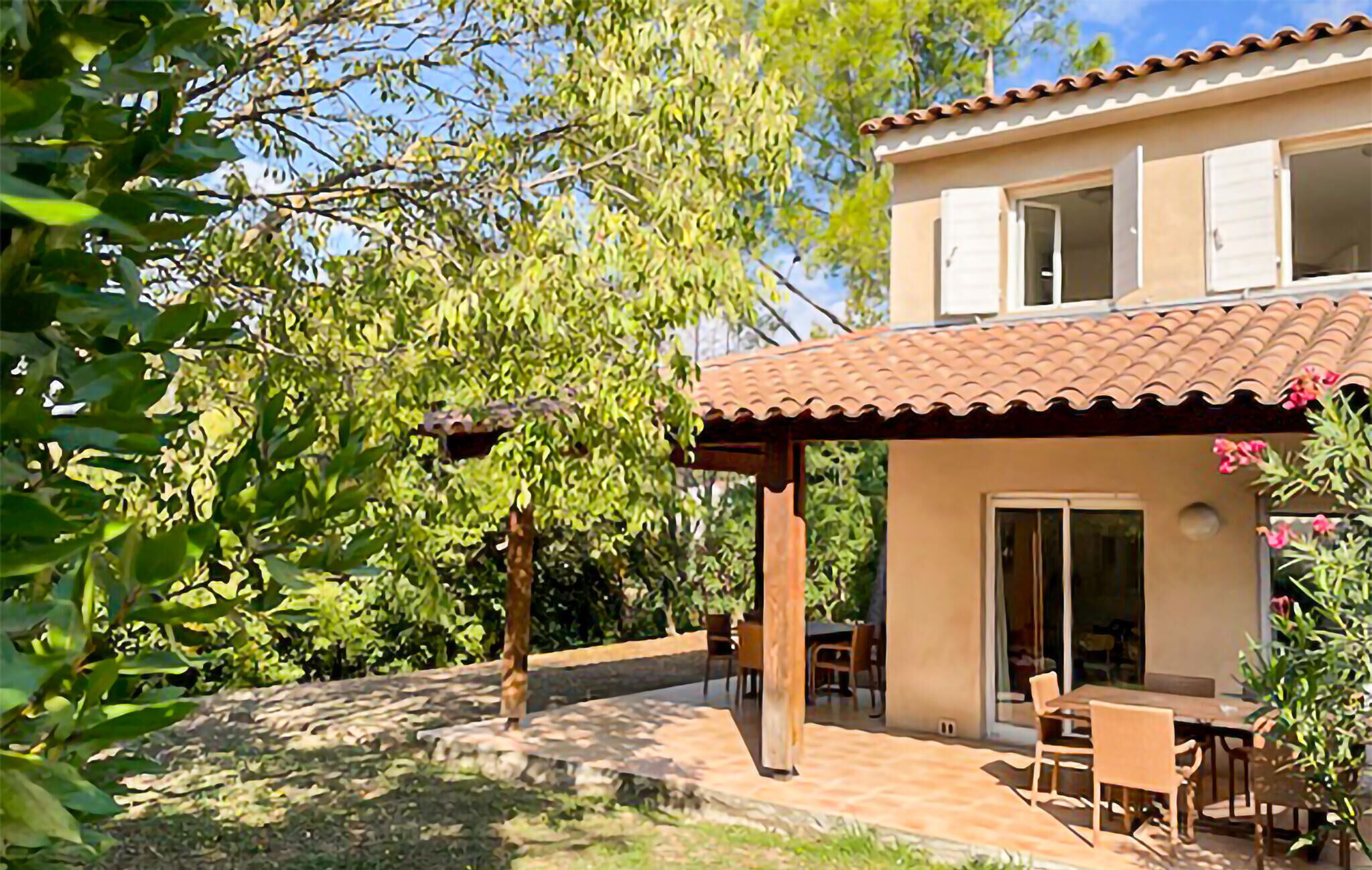 A two-story house with a patio area, a dining table, and chairs.