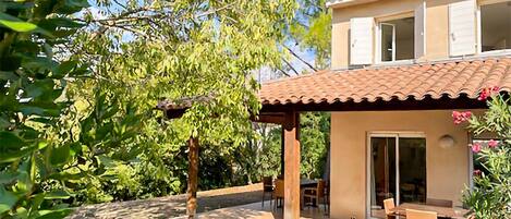 A two-story house with a patio area, a dining table, and chairs.