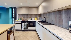 Eine moderne Küche mit weißen Schränken, einem eingebauten Backofen und einer Arbeitsplatte aus Granit.