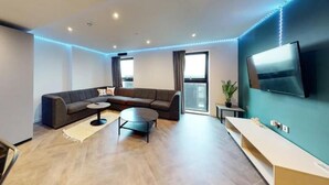 Ein modernes Wohnzimmer mit einem Ecksofa, einem Couchtisch und einem flachbildfernseher an der Wand.