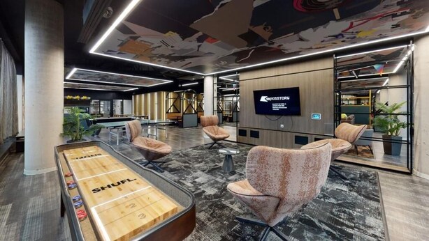Ein stilvoller Lounge-Bereich mit Shuffleboard-Tisch, bequemen Sitzgelegenheiten und einem großen Bildschirm, der den Namen 'KISSTOR' anzeigt.