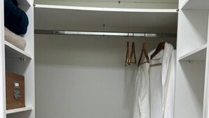 A walk-in closet with shelves, a hanging robe, and storage bins. - Air-conditioned family home (Cachoeira do Bom Jesus)