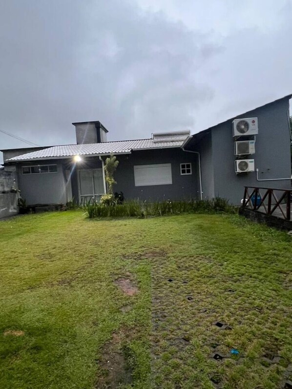 Un edificio residencial con un patio cubierto, unidades de aire acondicionado y un césped.
