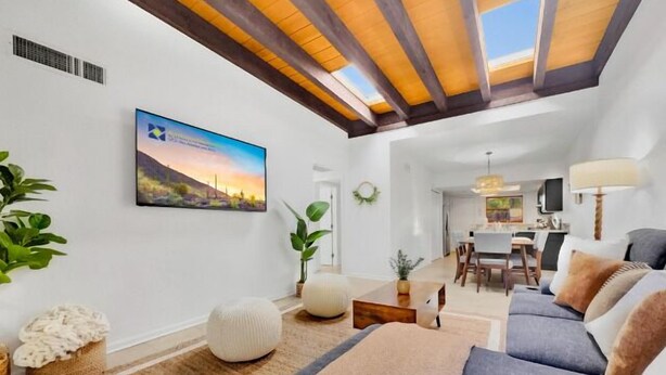 A modern living room with a high ceiling, a dining area, and a kitchen in the background. - 3BR patio home w community pool, heated spa (Tucson)