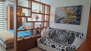 Un dormitorio con una cama, un panel de madera, un sofá y un cuadro colgado en la pared.