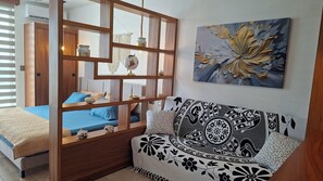 Ein Schlafzimmer mit einem Bett, einer Holzwand, einer Couch und einem Wandbild.