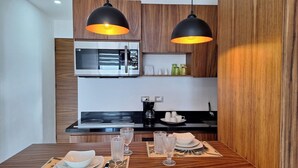 Una cocina moderna con horno empotrado, cafetera y dos lámparas colgantes.