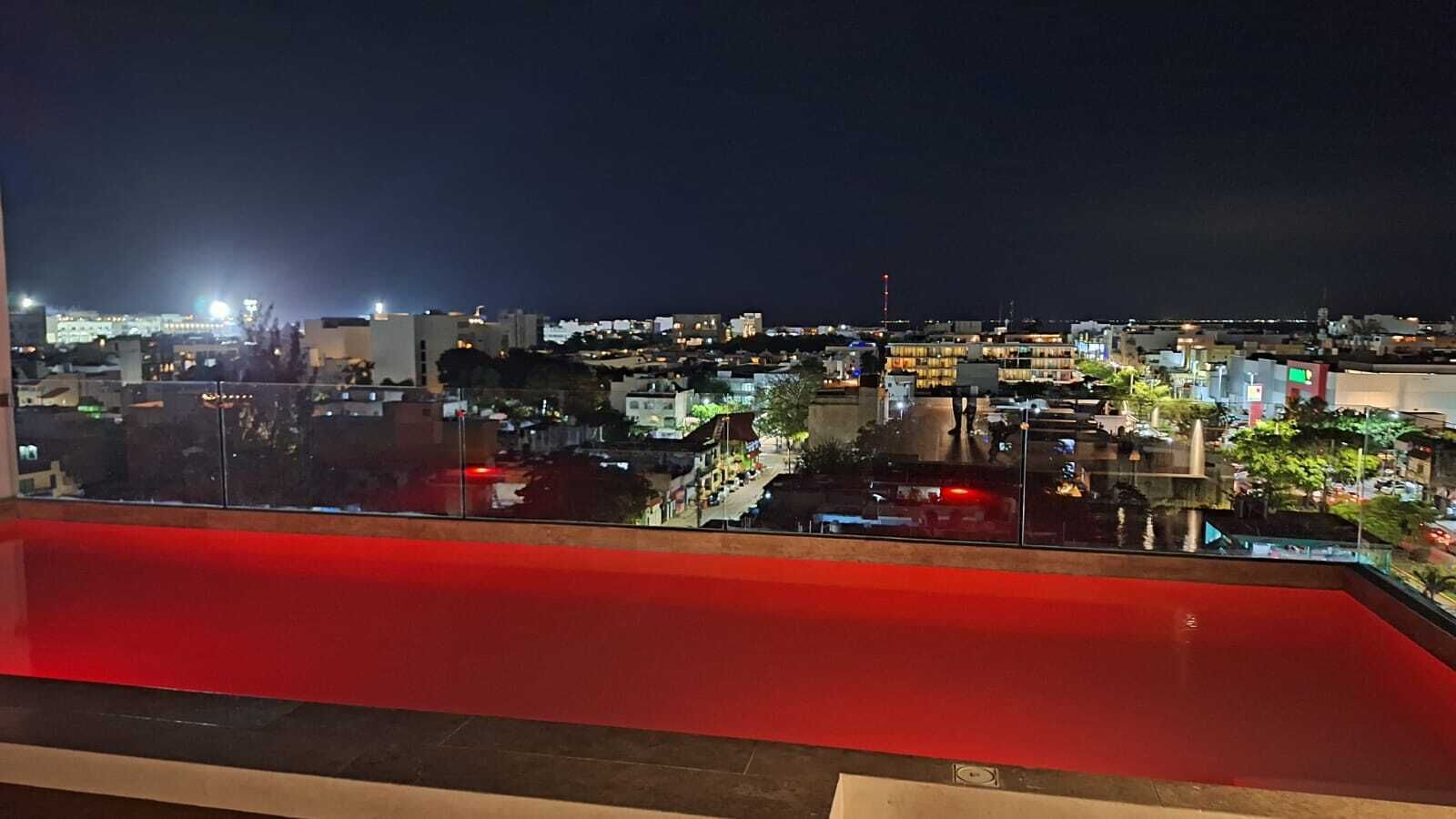Bybillede natten over, set fra en balkon med rødt gelænder.