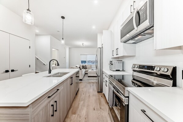 A modern kitchen with white cabinetry, stainless steel appliances, and a central island.