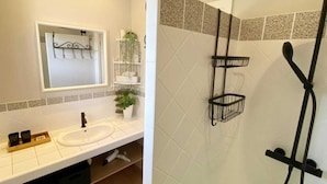 A bathroom with a white sink, a mirror, a plant, and a shower with a black hose. - Villa La Fourmilière heated pool walking distance to beach (Lecci)