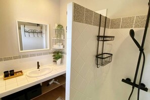 A bathroom with a white sink, a mirror, a plant, and a shower with a black hose. - Villa La Fourmilière heated pool walking distance to beach (Lecci)