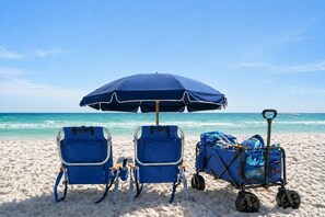 Two beach chairs and a beach cart with a blue umbrella on a sandy beach. - Gulf Views! 2-Min Walk to Private Beach, Dog Friendly, Luxury 3 Story Retreat (Miramar Beach)