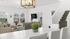 En moderne stue med spisebord, sofaer, et fjernsyn og en trappe.