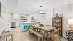 A modern kitchen with white cabinets, a central island, and teal bar stools.