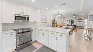 A modern kitchen with white cabinetry, stainless steel appliances, and a large island.