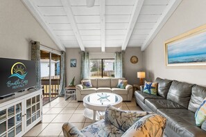 A living room with a sofa, a glass-top coffee table, and a television on a cabinet. - Free Beach Service~2 Min to the Beach~Gulf View~Pool~Private Beach Access~Chateau La Mer 1C (Destin)