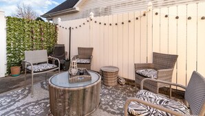 A patio with wicker furniture, a glass table, and a white fence. - Stylish 2BR Townhome w/ Garage & Patio Perfect for Stays or Assignments (Clarksville)
