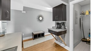 Una cucina moderna con pareti grigie, mobili scuri, una macchina da caffè e una piccola panca.