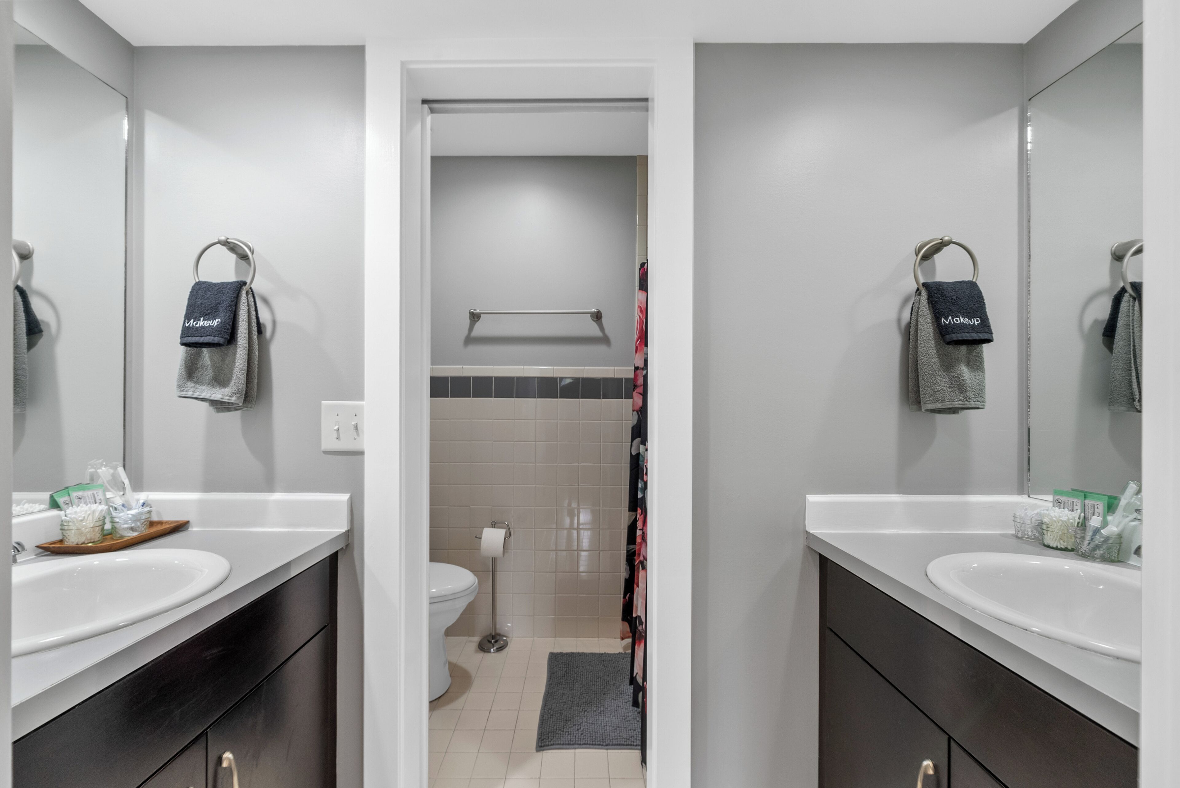 A modern bathroom with two sinks, a toilet, and a shower area.