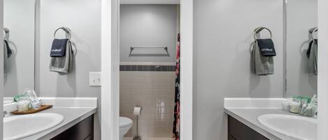 A modern bathroom with two sinks, a toilet, and a shower area.
