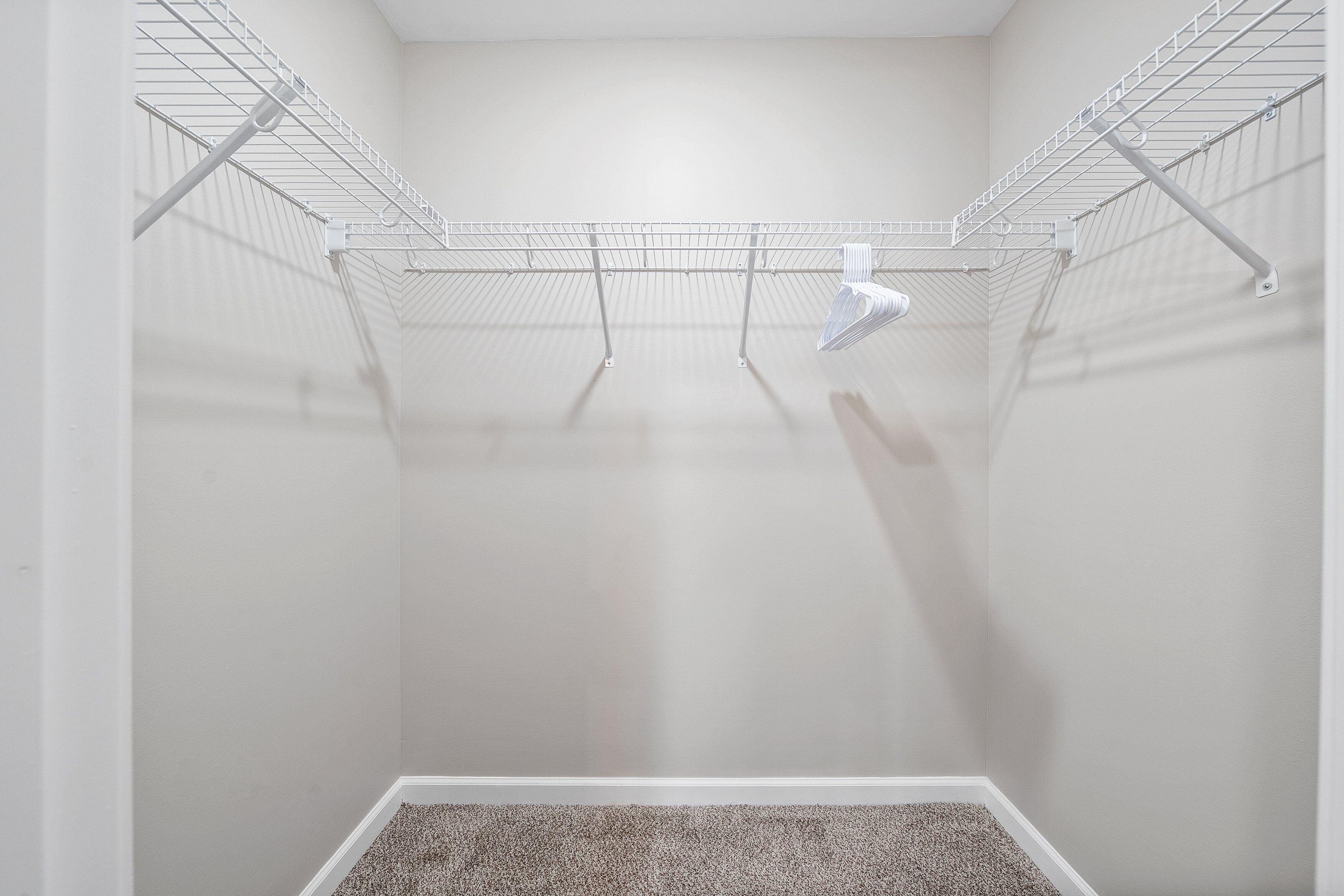 A walk-in closet with metal shelving and a carpeted floor.