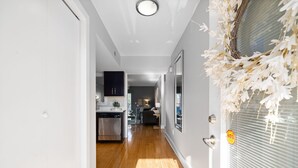 Un pasillo con suelo de madera que conduce a una zona de cocina con electrodomésticos modernos y un comedor.