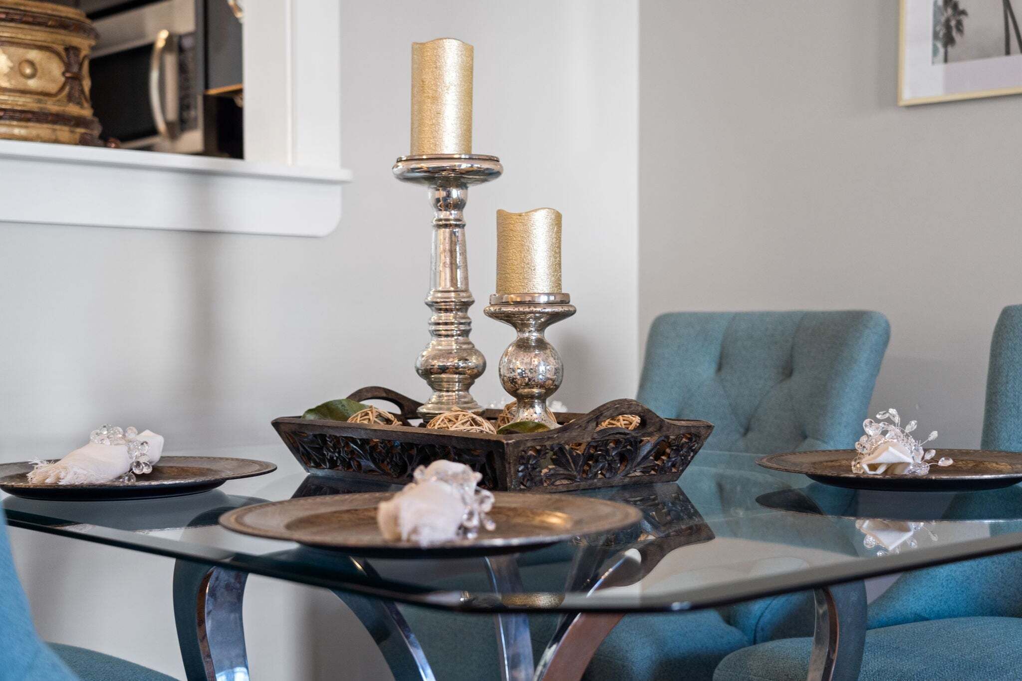 A dining table with ornate candle holders, a decorative bowl, and a blue upholstered chair.