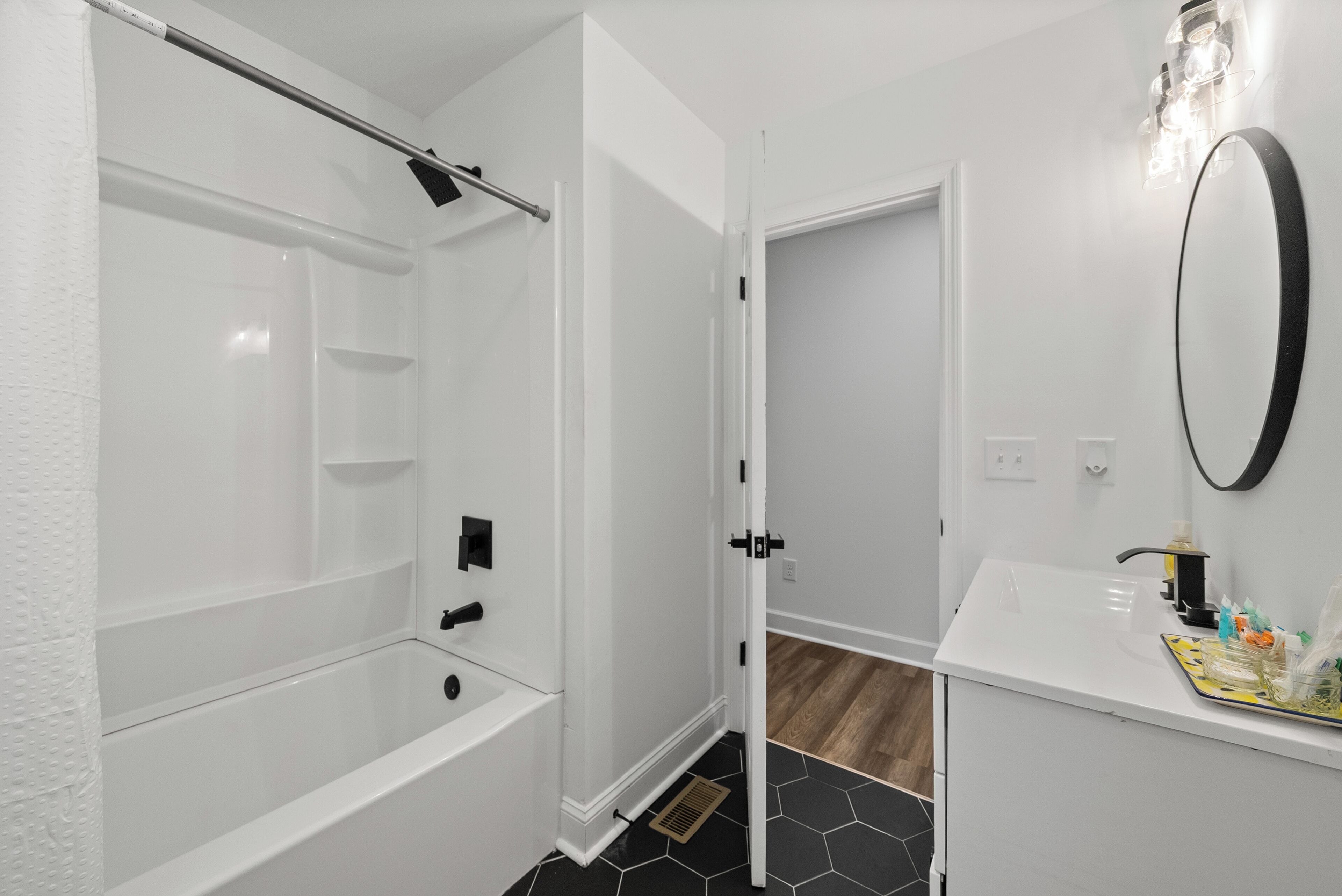 A modern bathroom with a white bathtub, a shower, and a sink with a mirror.