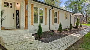 A white brick house with a front porch, numbered 1221, and a 'HELLO there' sign. - Bertin's Place (Clarksville)