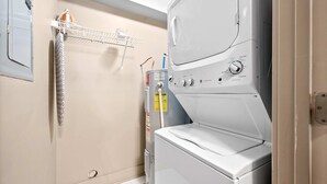 A laundry area with a front-loading washer and dryer, a towel rack, and a water heater. - Loft #105 (Clarksville)
