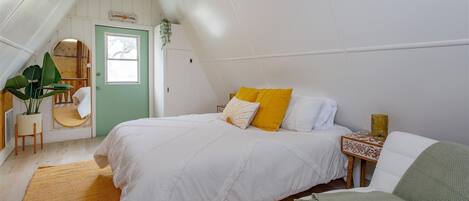 Une chambre à coucher avec un lit, une table de chevet, une chaise, un miroir et une porte.