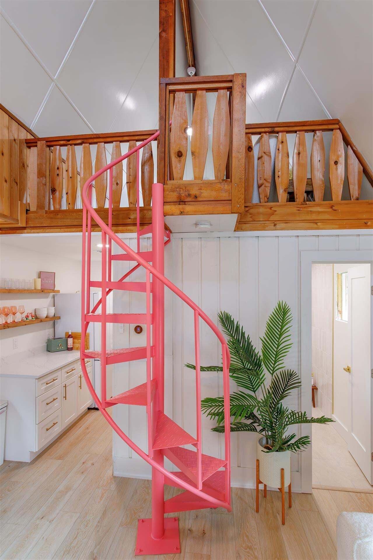 A modern interior with a spiral staircase, wooden beams, a white wall, and a potted plant.