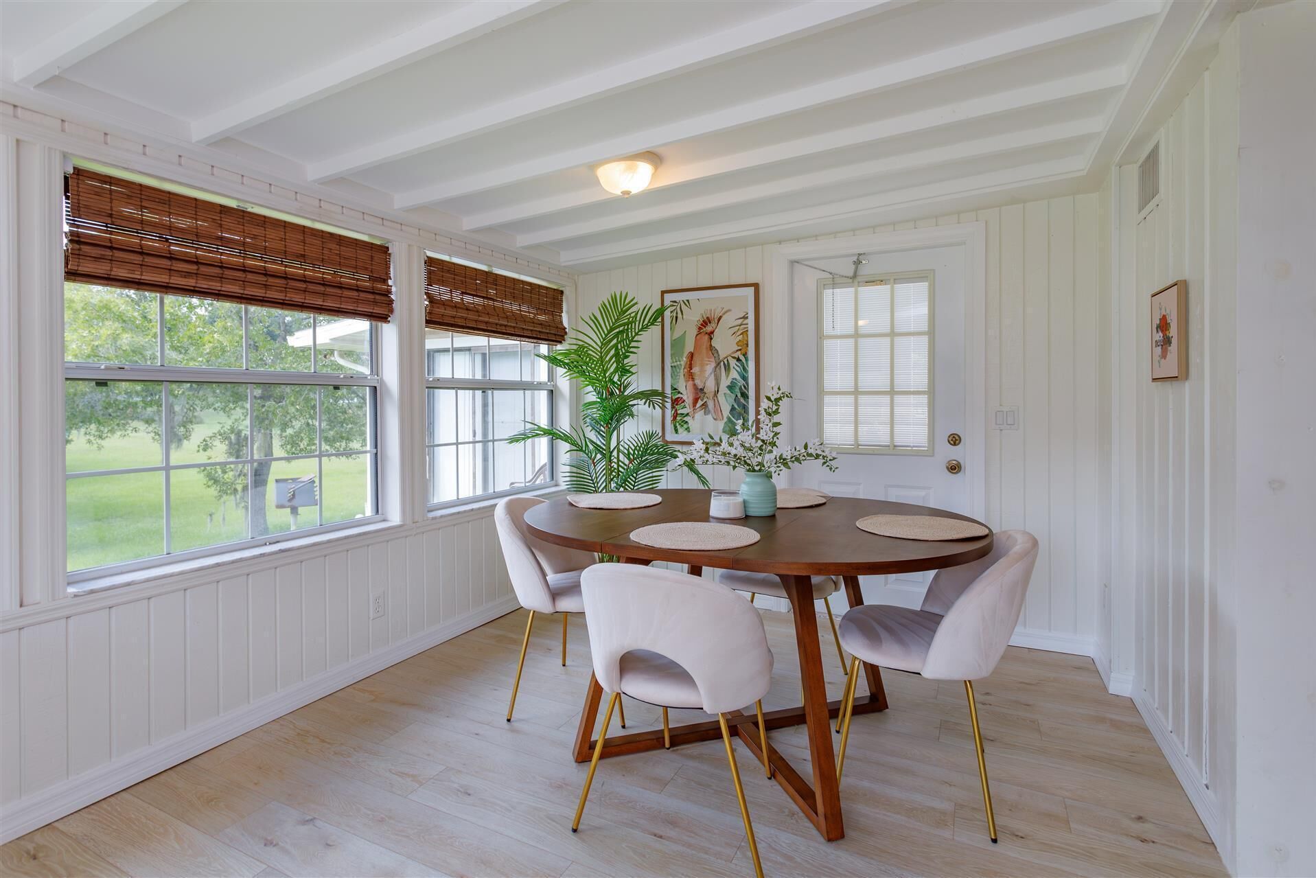 Un coin repas avec une table ronde en bois, quatre chaises et une plante en pot.