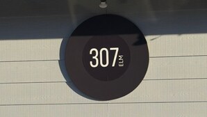 A circular sign with the number 307 on a building facade.