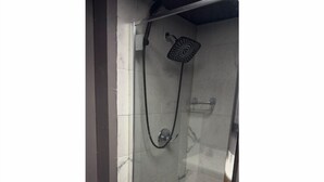 A shower with a handheld showerhead and a wall-mounted faucet.