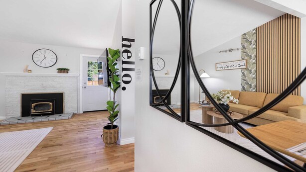 Een moderne woonkamer met een open haard, een bank en een spiegel die de kamer weerspiegelt.