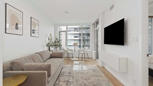 Una sala de estar moderna con un sofá, una mesa de centro y un televisor montado en la pared.