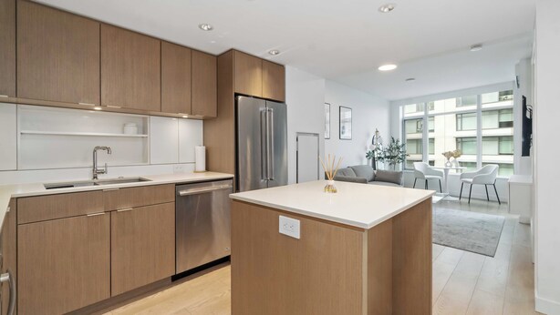 Una cocina moderna con armarios de madera, un refrigerador de acero inoxidable y una isla central.