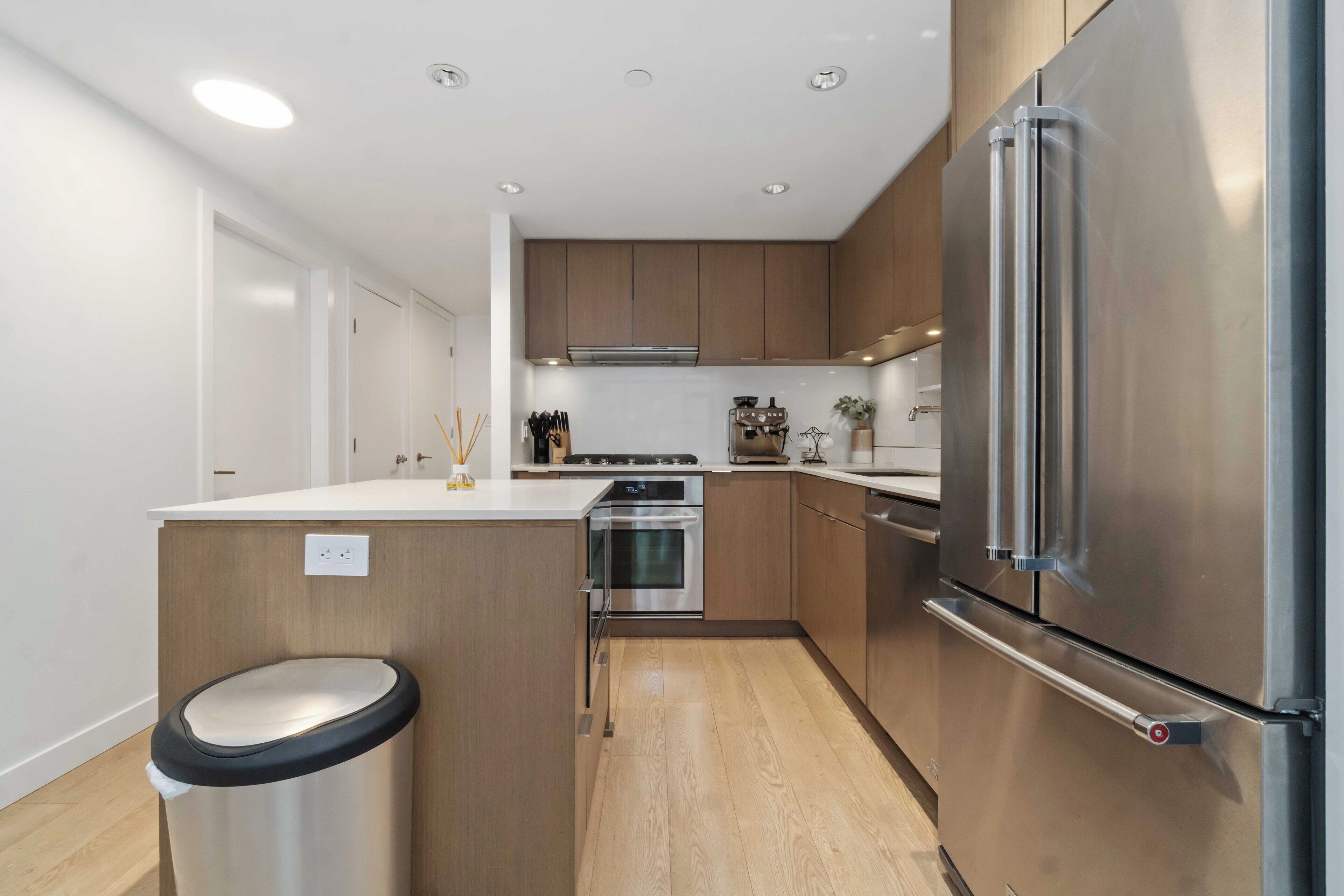 Una cocina moderna con electrodomésticos de acero inoxidable, armarios de madera y una isla central.