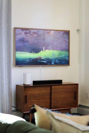 Ein Flachbildfernseher ist an einer Wand über einem Holzschrank angebracht, auf dem sich eine Fernbedienung befindet.