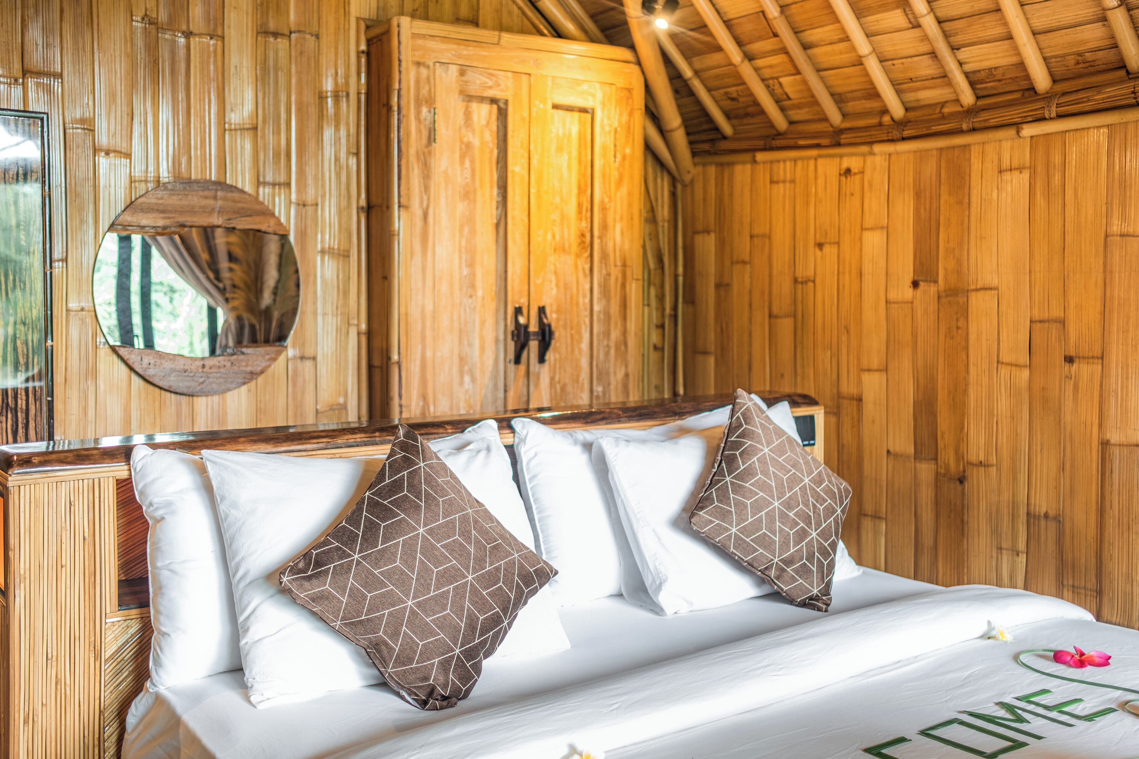 A wooden room with a bed, a mirror, and a wardrobe.