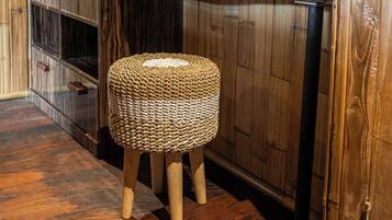 Une coiffeuse en bois avec un miroir, un tabouret en osier et un plancher en bois.