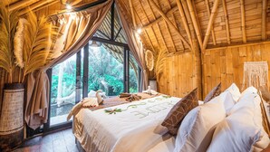 A room with a bed, large windows, and a view of greenery outside. - Sindu Village Ubud (Ubud)