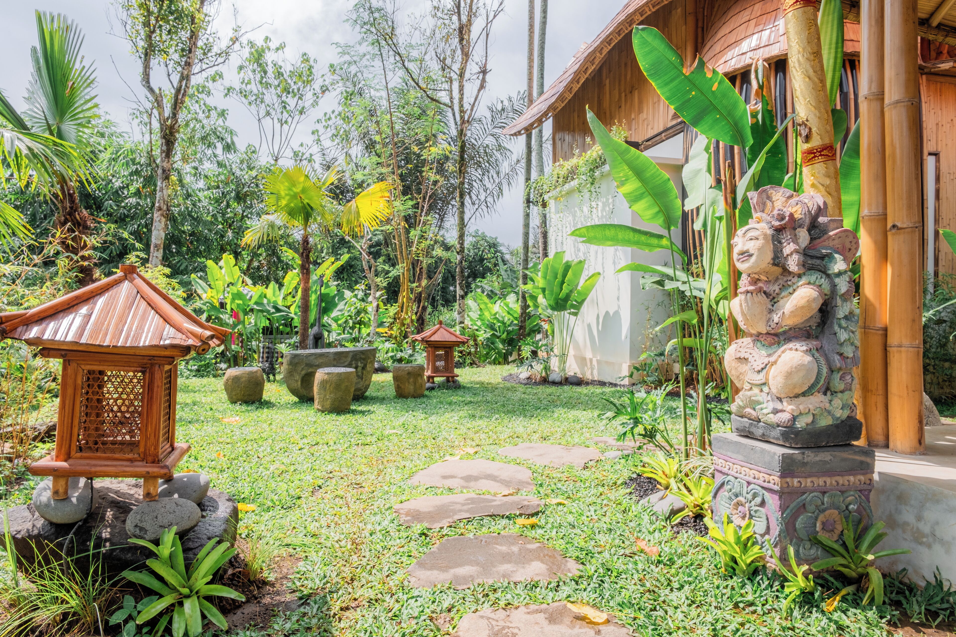 A garden with stone pathways, a wooden lantern, and a statue.