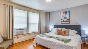 A bedroom with a bed, a window with curtains, a radiator, and a painting on the wall. - Safe Area W/ Balcony - Great for Travel Nurses (Wichita)
